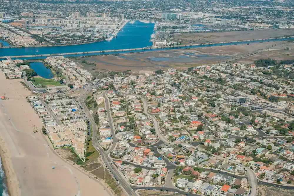 Aerial view of Playa del Rey, California, showing coastal homes, Ballona Wetlands, Marina del Rey Harbor, and the Pacific coastline.