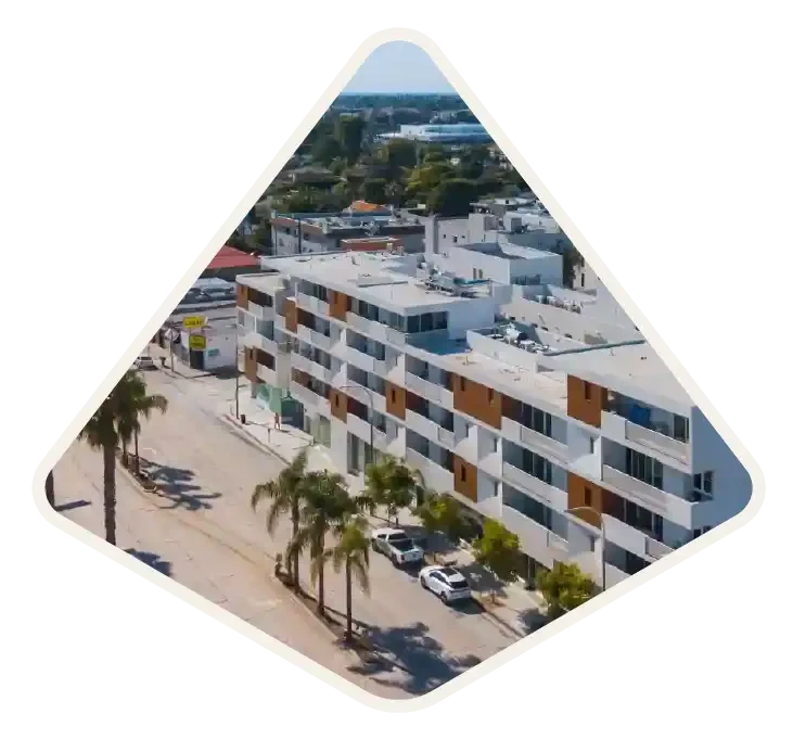 Aerial view of a modern apartment building on a palm-lined street in Culver City, CA