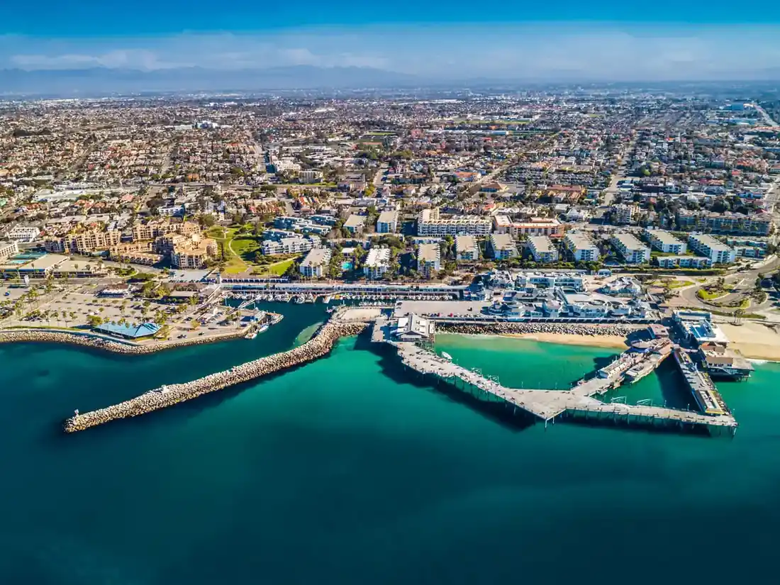 Wide aerial view of Redondo Beach, California, showing King Harbor, coastal residential neighborhoods, the marina, and the surrounding South Bay community