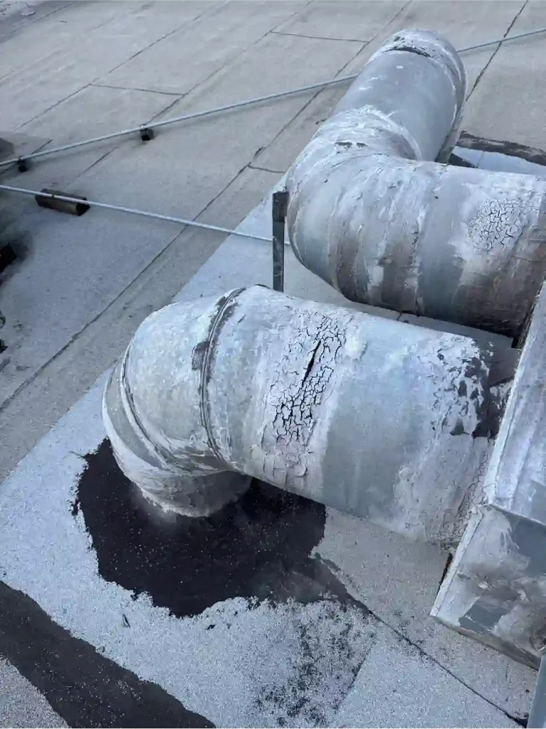 Metal pipe boot and flashing collar sealed with black roofing sealant around a conduit