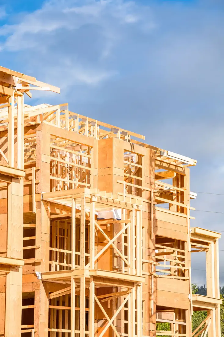 Residential home framing under construction with exposed wood framing, roof structure, and second-story exterior walls before exterior finishes