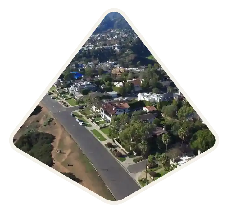 Large homes on a tree-lined residential street running along the bluff in Pacific Palisades, CA